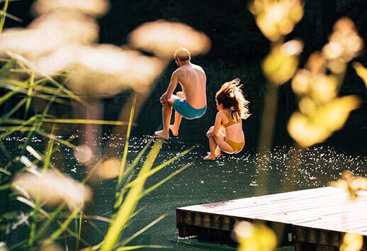 Two young people jump into the Seewaldsee in Fontanella.