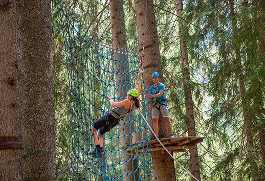 Two young people climb in the forest ropes course in Damüls.