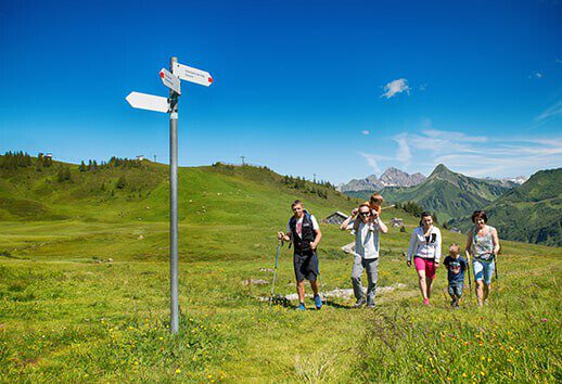 Family hiking in Damüls/Faschina and looking at the signpost.